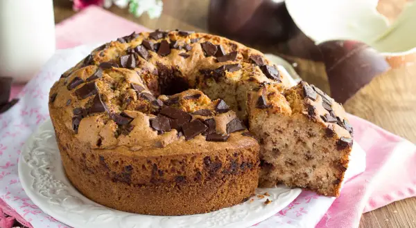 Ciambellone soffice con gocce di cioccolato, perfetto per la colazione di Pasqua. Accanto, uova di Pasqua al cioccolato.