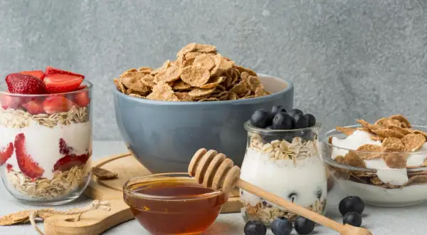 Colazione sana con cereali, yogurt, fragole e mirtilli. Un tocco di miele per dolcificare.