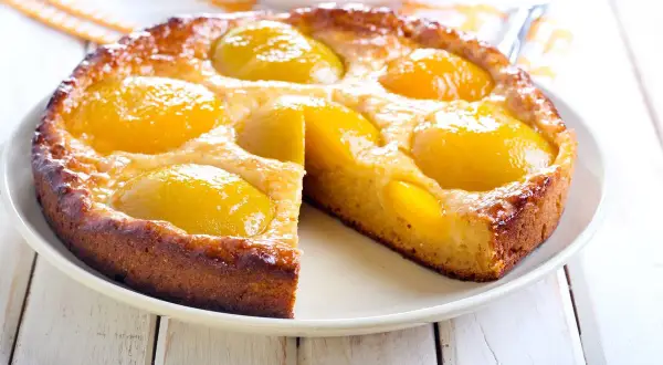 Torta soffice con pesche sciroppate dorate, un dolce profumato e invitante, perfetto per ogni occasione.