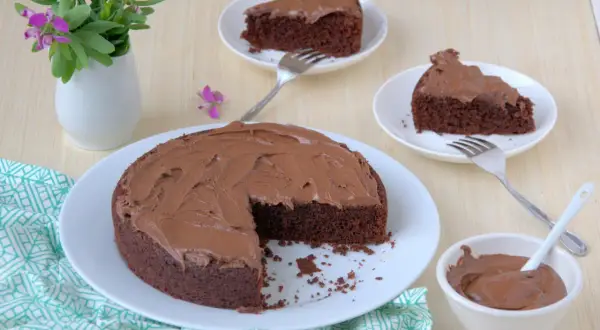 Una deliziosa torta al cioccolato senza glutine, con una fetta mancante e altre due servite su piattini, pronte per essere gustate.