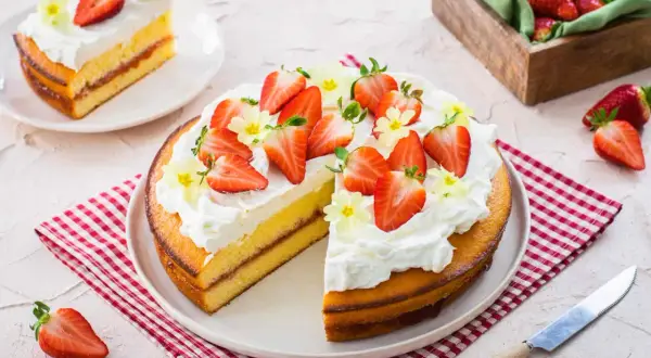 Una deliziosa torta alle fragole, con panna montata e fragole fresche, pronta per essere gustata.