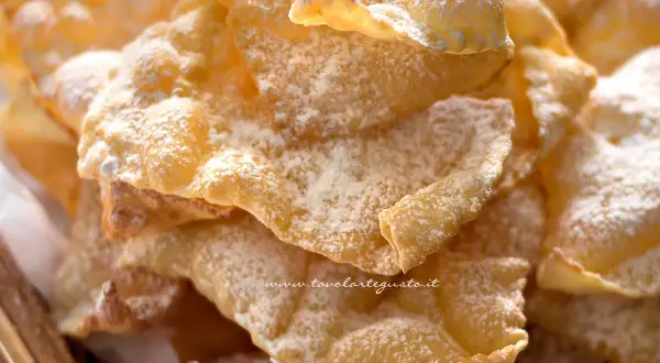 Chiacchiere croccanti, una deliziosa chiacchiere ricetta della nonna, cosparse di zucchero a velo.
