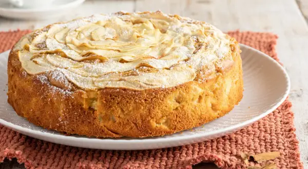 Una deliziosa torta di mele senza burro, decorata con fettine di mela e zucchero a velo, pronta per essere gustata.