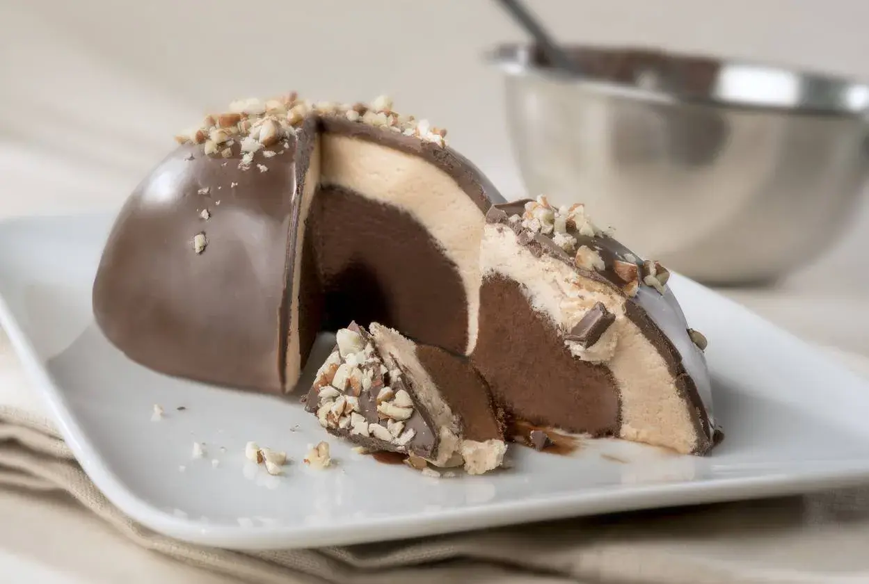 Un delizioso tartufo alla nocciola, con strati di gelato al cioccolato e crema, ricoperto di cioccolato e granella di nocciole.