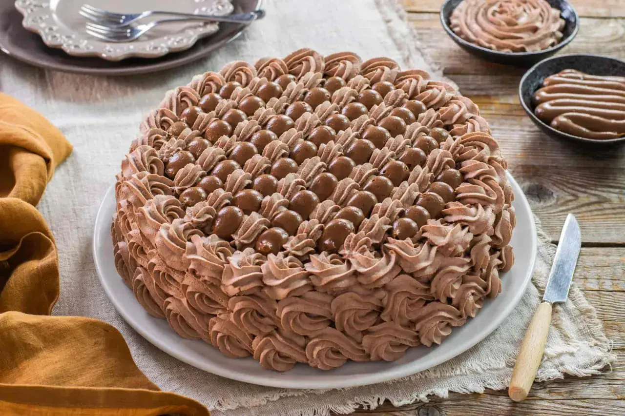 Torta decorata con abbondante crema chantilly al cioccolato e praline. Un dolce invitante pronto per essere gustato.
