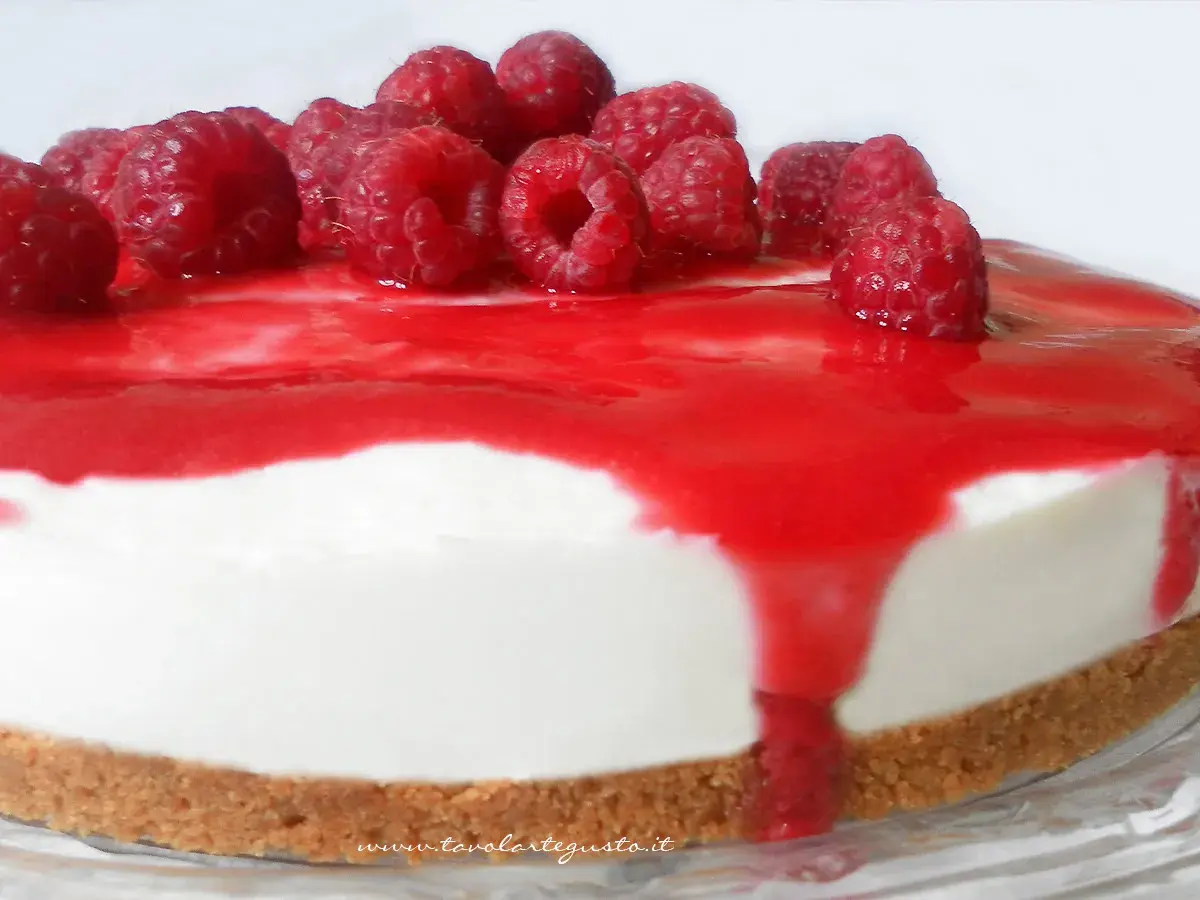 Cheesecake ai lamponi con coulis rosso e lamponi freschi, una delizia per gli occhi e per il palato.