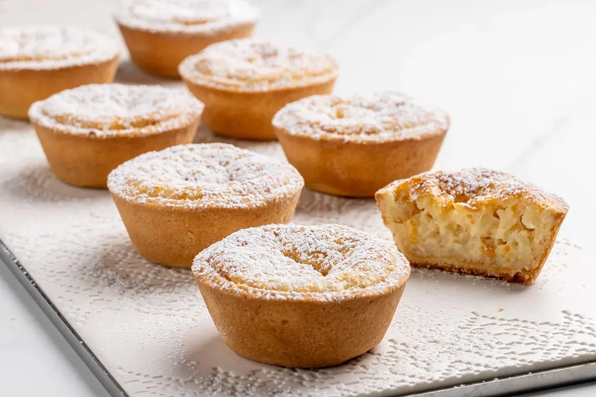 Piccoli dolci veloci, crostate con ripieno cremoso e spolverata di zucchero a velo, perfetti per una pausa golosa.