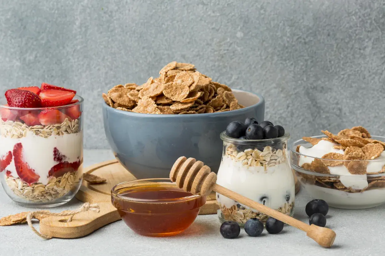Colazione sana con cereali, yogurt, fragole e mirtilli. Un tocco di miele per dolcificare.