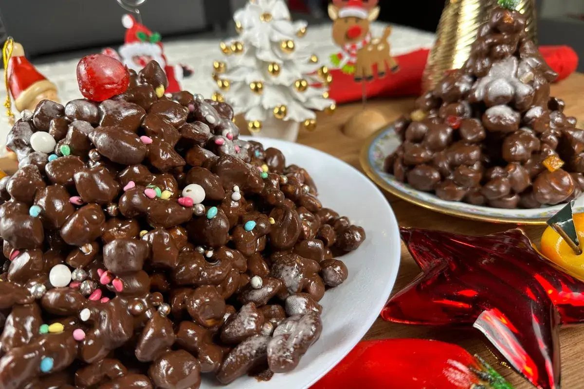 Deliziosi struffoli al cioccolato, decorati con zuccherini colorati e perline argentate, pronti per le feste natalizie.