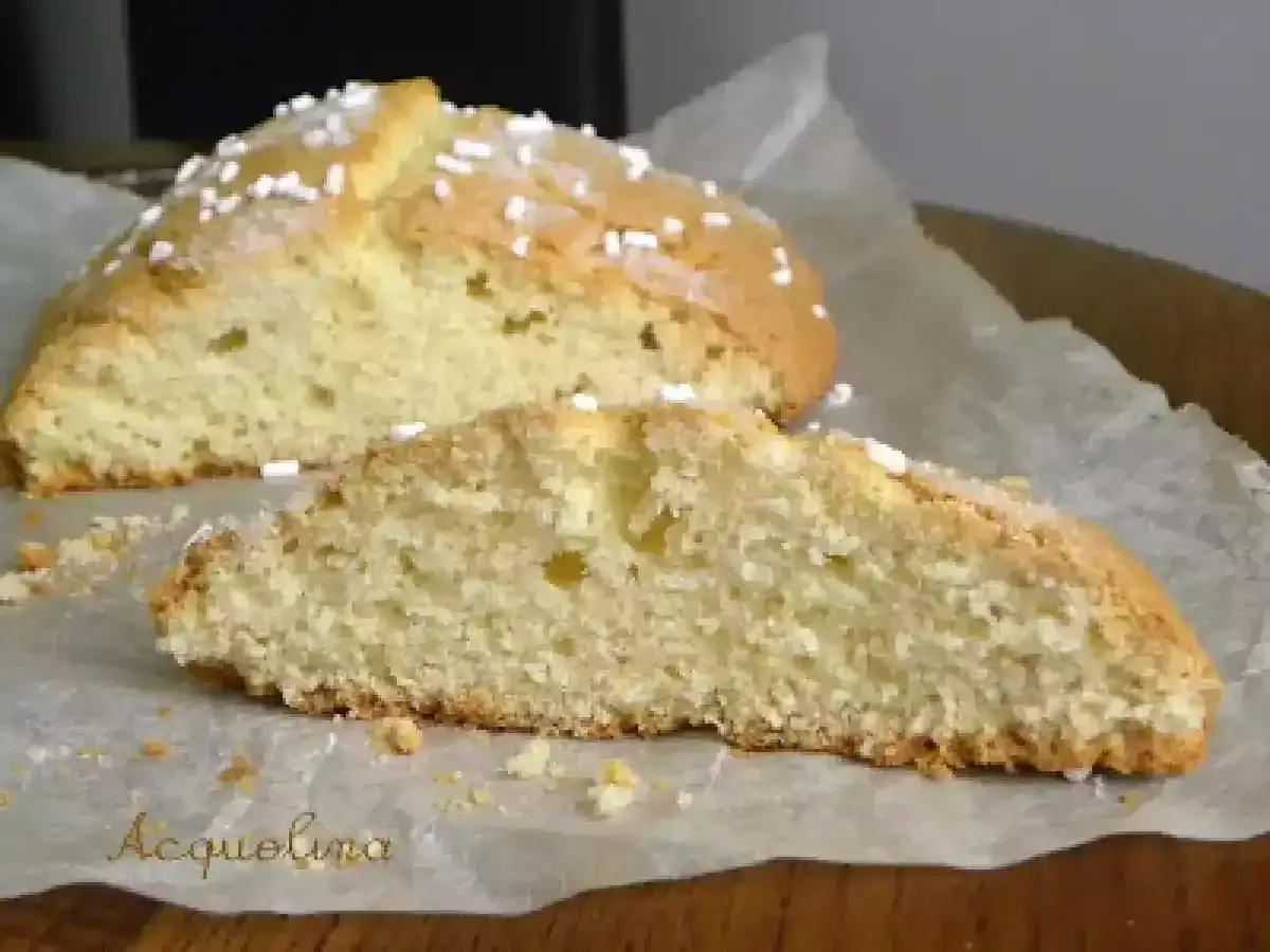 Fetta di ciambella romagnola soffice e dorata, cosparsa di zuccherini, su carta da forno.