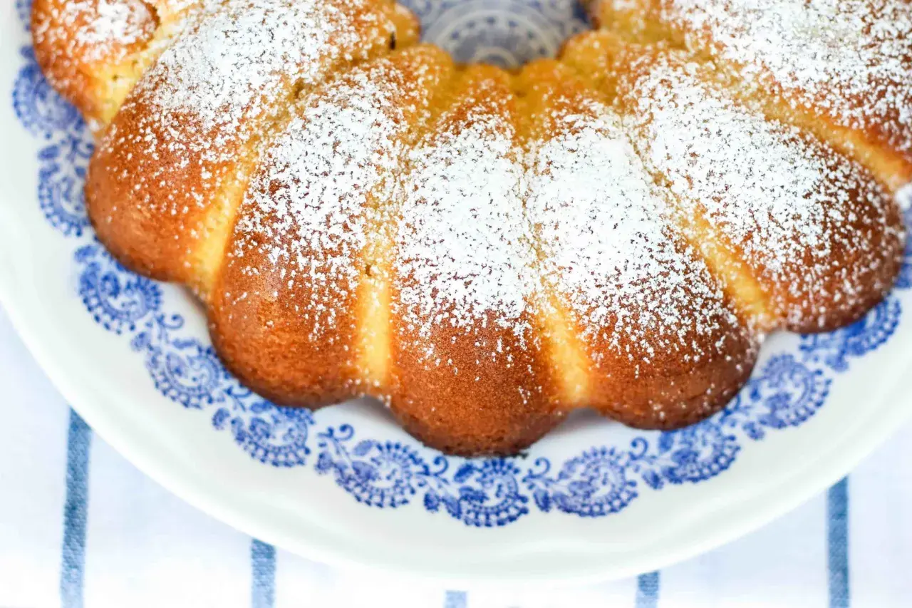 Deliziosa torta al latte caldo, cosparsa di zucchero a velo, su un piatto con decori blu.