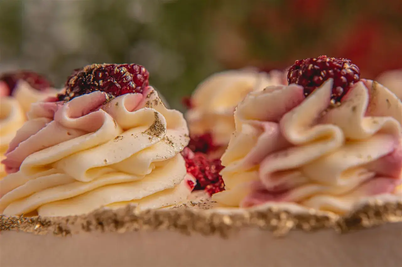 Deliziosi torte gelato e semifreddi decorati con crema rosa e gialla, lamponi e polvere dorata.