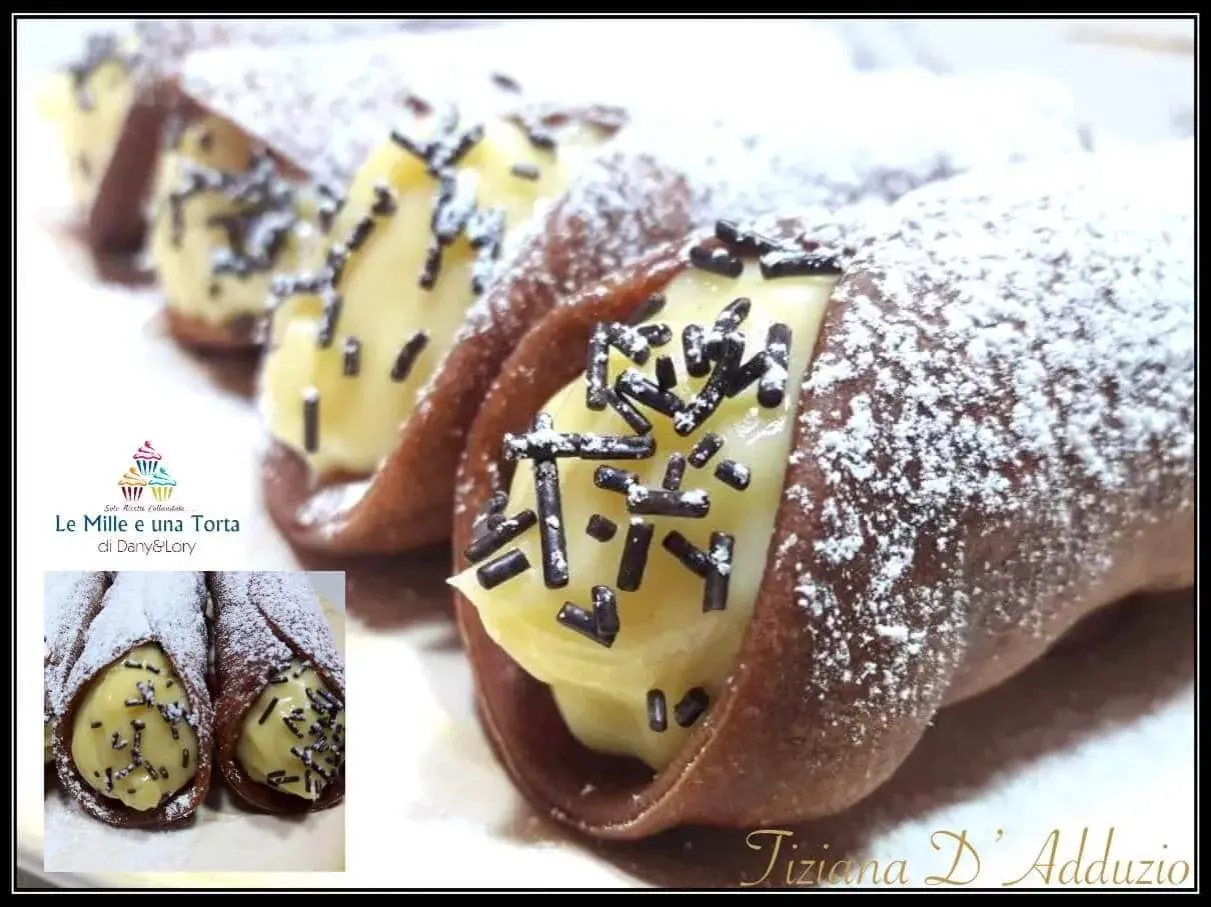 Cannoli siciliani con golosa crema al cioccolato, spolverati di zucchero a velo e granella scura. Un dolce irresistibile!