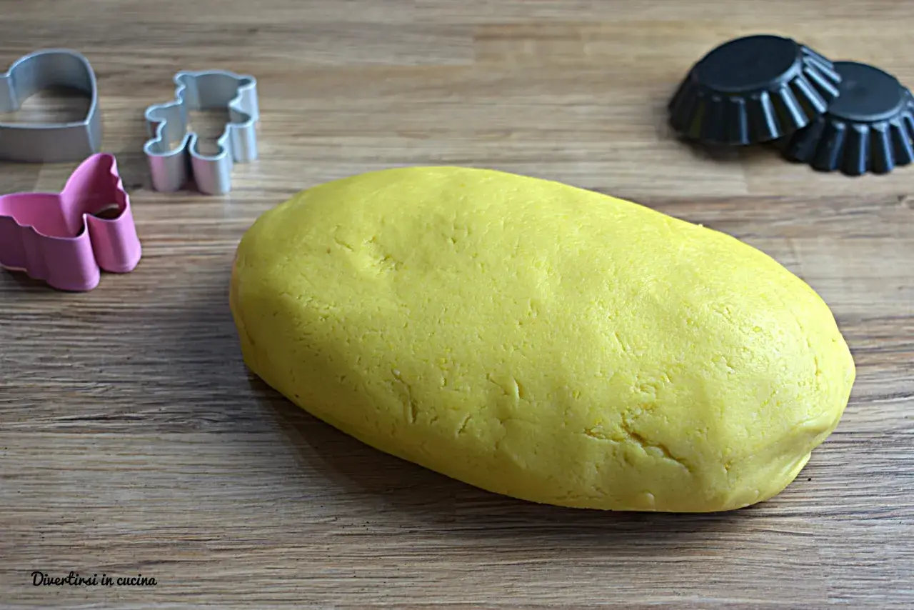 Impasto giallo per pasta frolla Bimby pronto per essere trasformato in biscotti con formine a orsetto, cuore e farfalla.