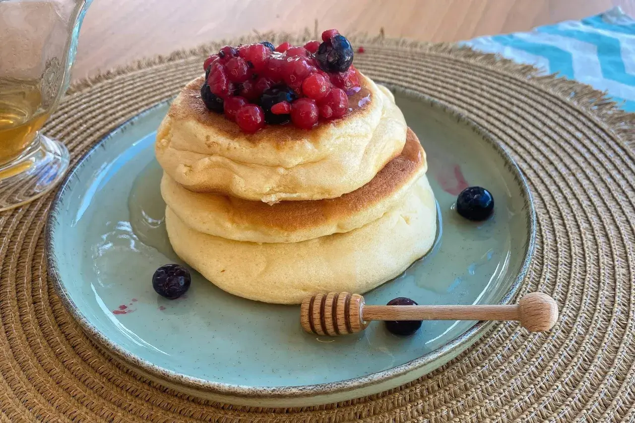 Pancake senza zucchero soffici e dorati, guarniti con frutti di bosco freschi e miele. Un dolce sano e delizioso.