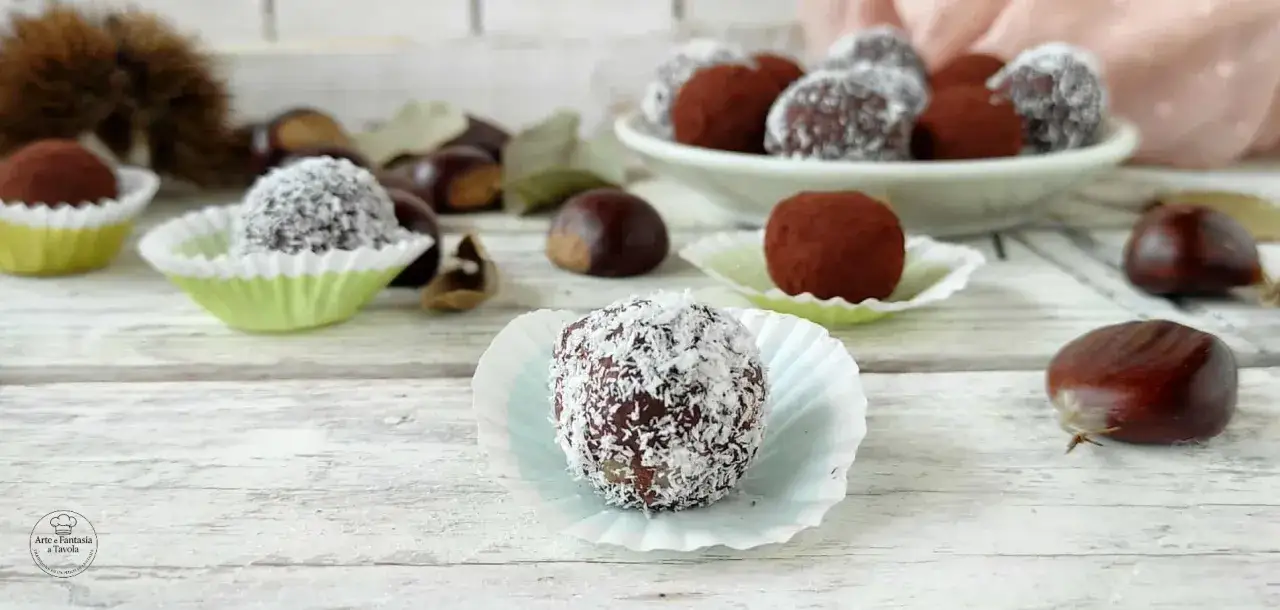 Deliziosi tartufini di castagne, alcuni ricoperti di cocco, altri di cacao, su un tavolo di legno con castagne fresche.