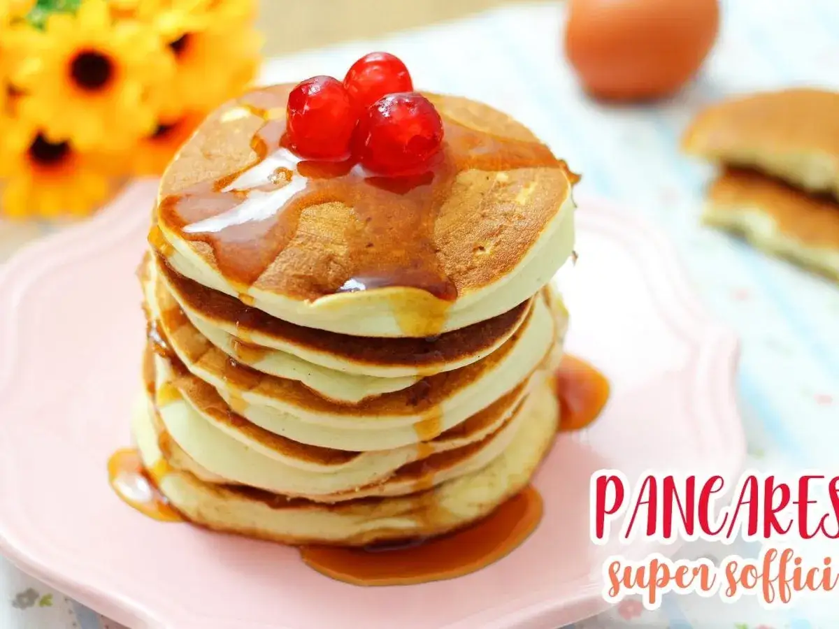 Pancakes soffici e dorati, guarniti con ciliegie e sciroppo d'acero. Perfetti per imparare come fare i pancake.