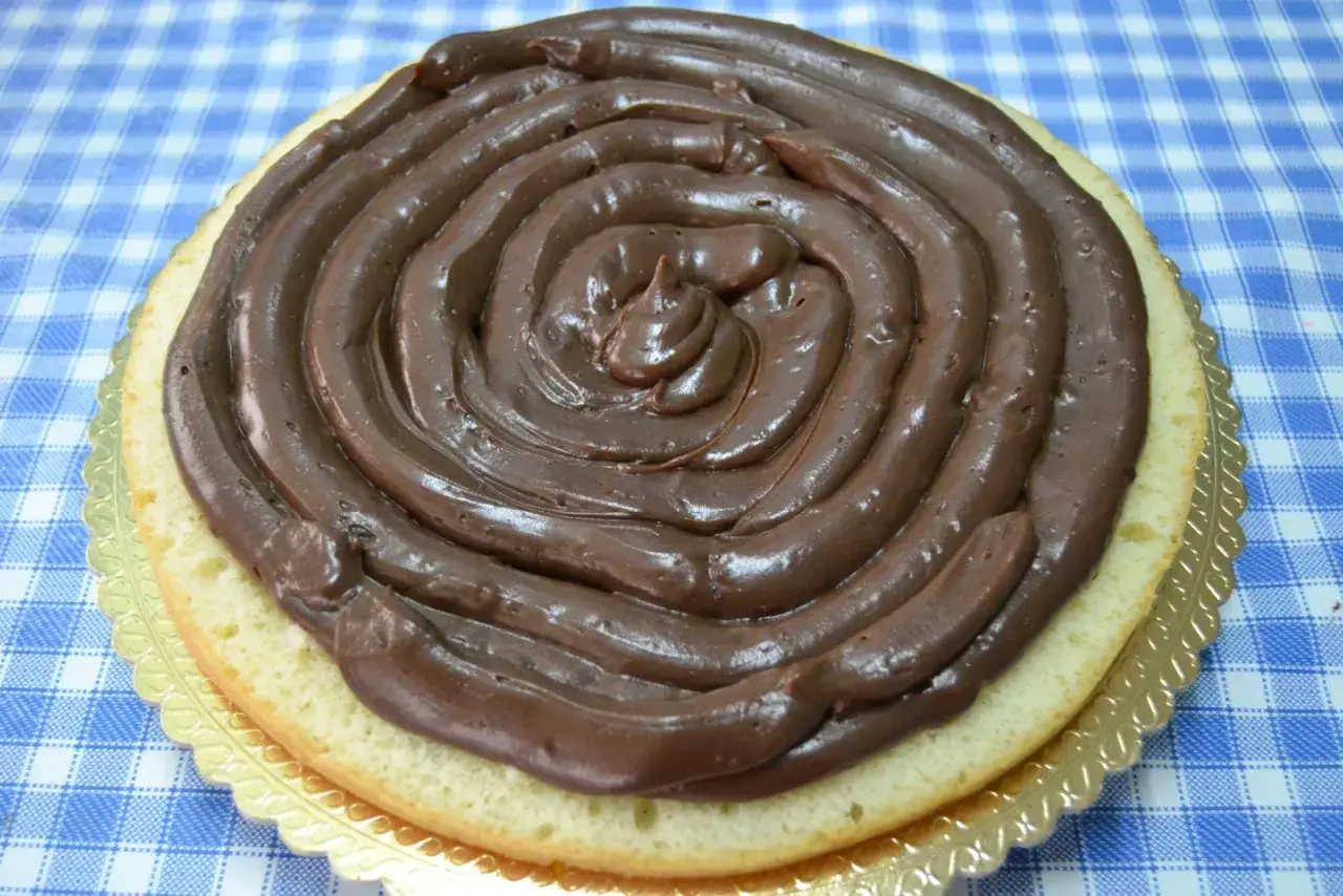 Torta moretta con glassa al cioccolato a spirale su base dorata, pronta per essere gustata.