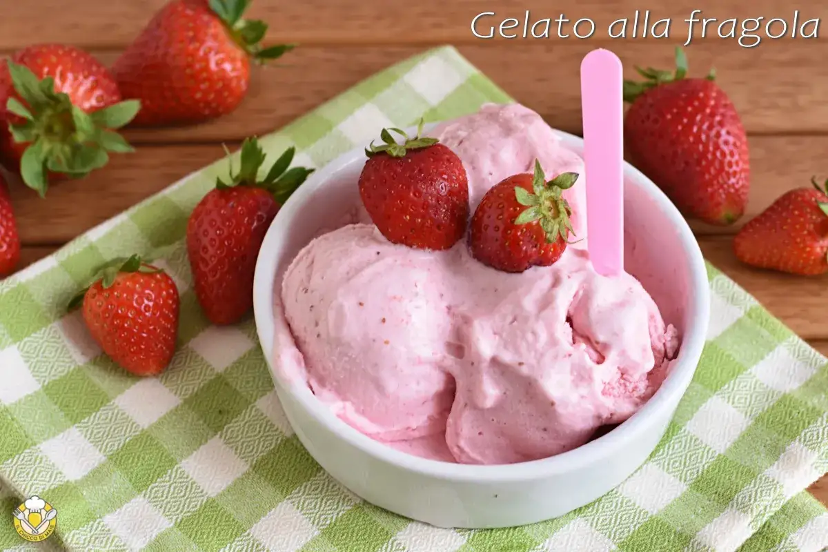 Coppa di cremoso gelato alla fragola, guarnita con fragole fresche, su un tovagliolo a quadretti verdi.