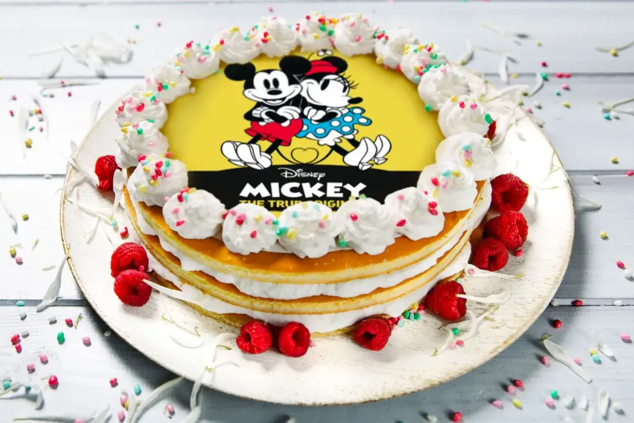 Torta con cialda di Topolino e Minnie, decorata con panna, lamponi e zuccherini colorati.