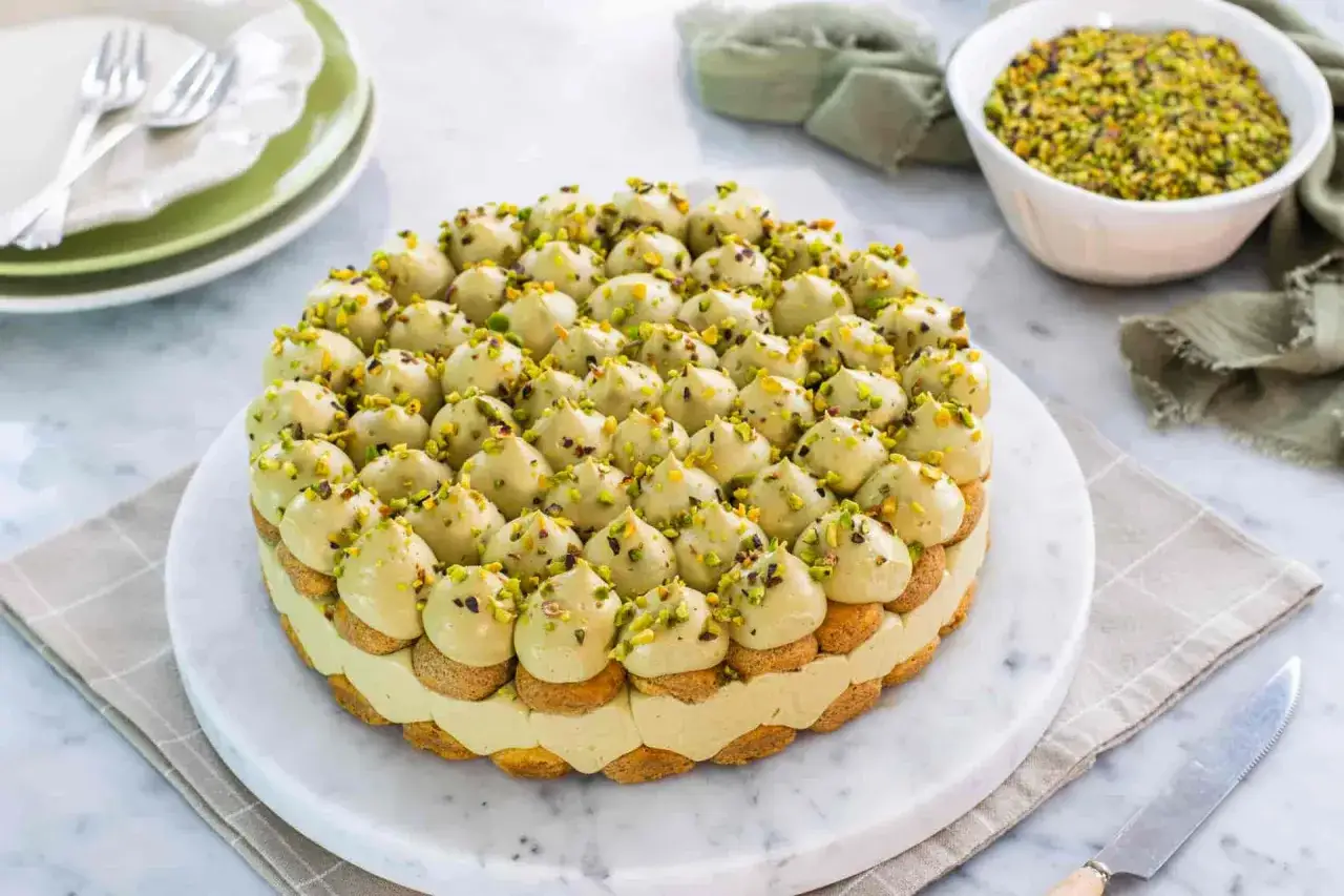 Un delizioso tiramisù al pistacchio, decorato con tante piccole meringhe verdi e granella di pistacchi.