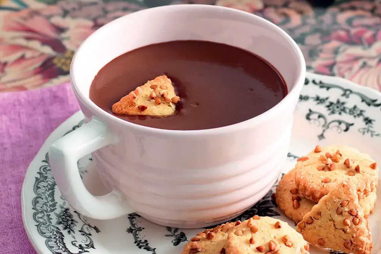 Una tazza di cioccolata calda fumante con biscotti croccanti. Perfetta per una pausa golosa.