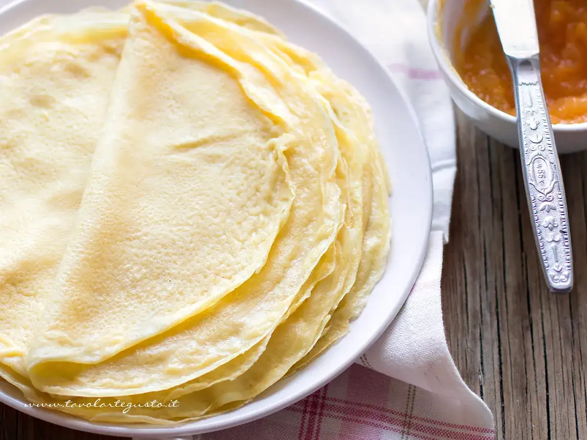 Piatto di crepes dorate, pronte per essere farcite. Una ricetta semplice e deliziosa per ogni occasione.