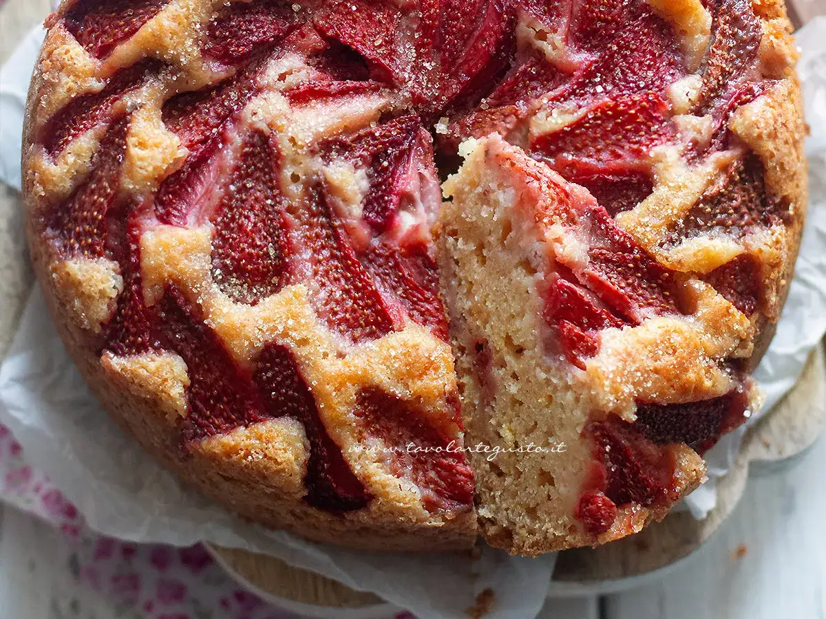 Torta vegana alle fragole, soffice e profumata, con una fetta tagliata che ne mostra la morbidezza.
