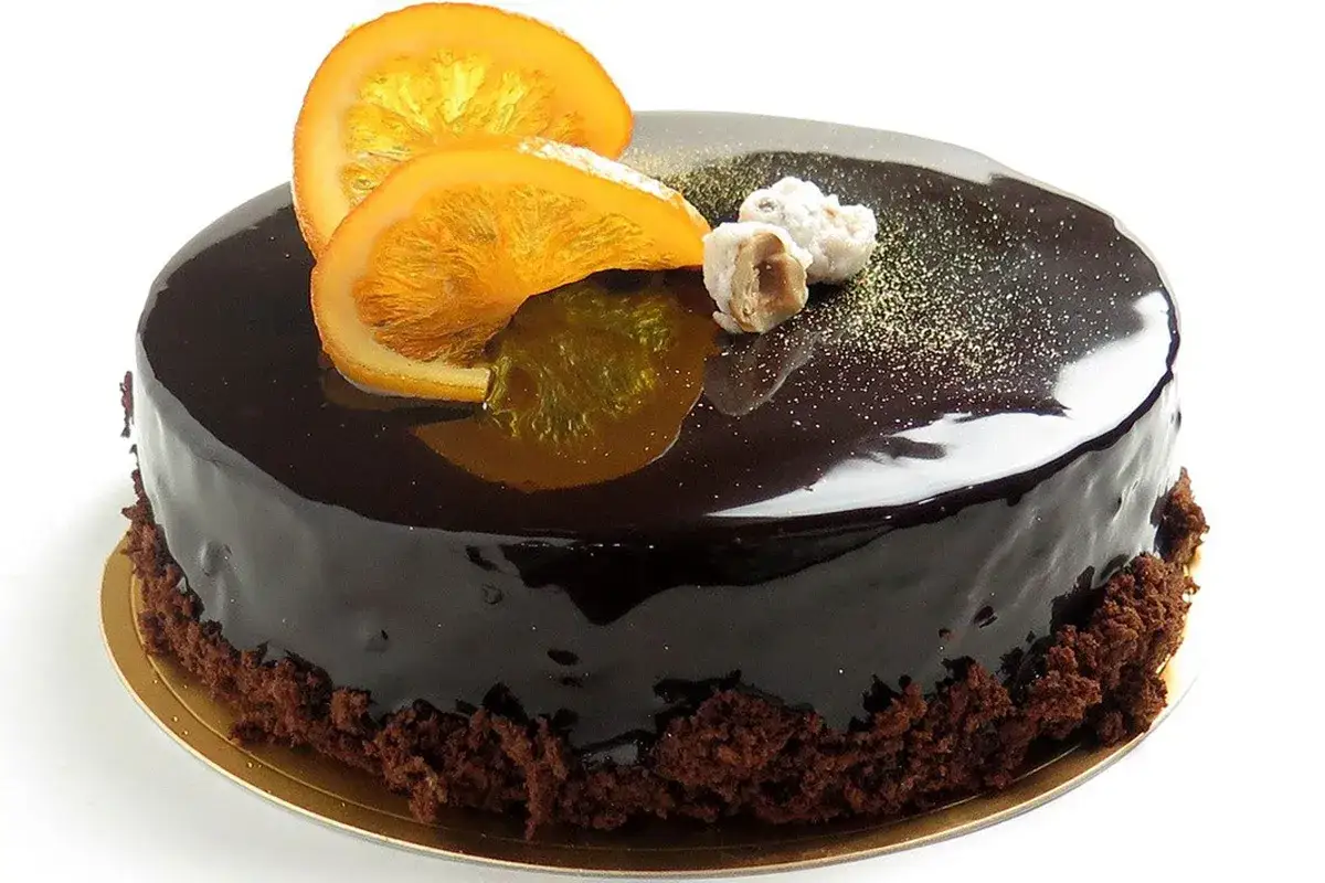 Torta lucida al cioccolato con fette d'arancia candita e nocciole. Un delizioso mousse cioccolato e arancia, perfetto per ogni occasione.