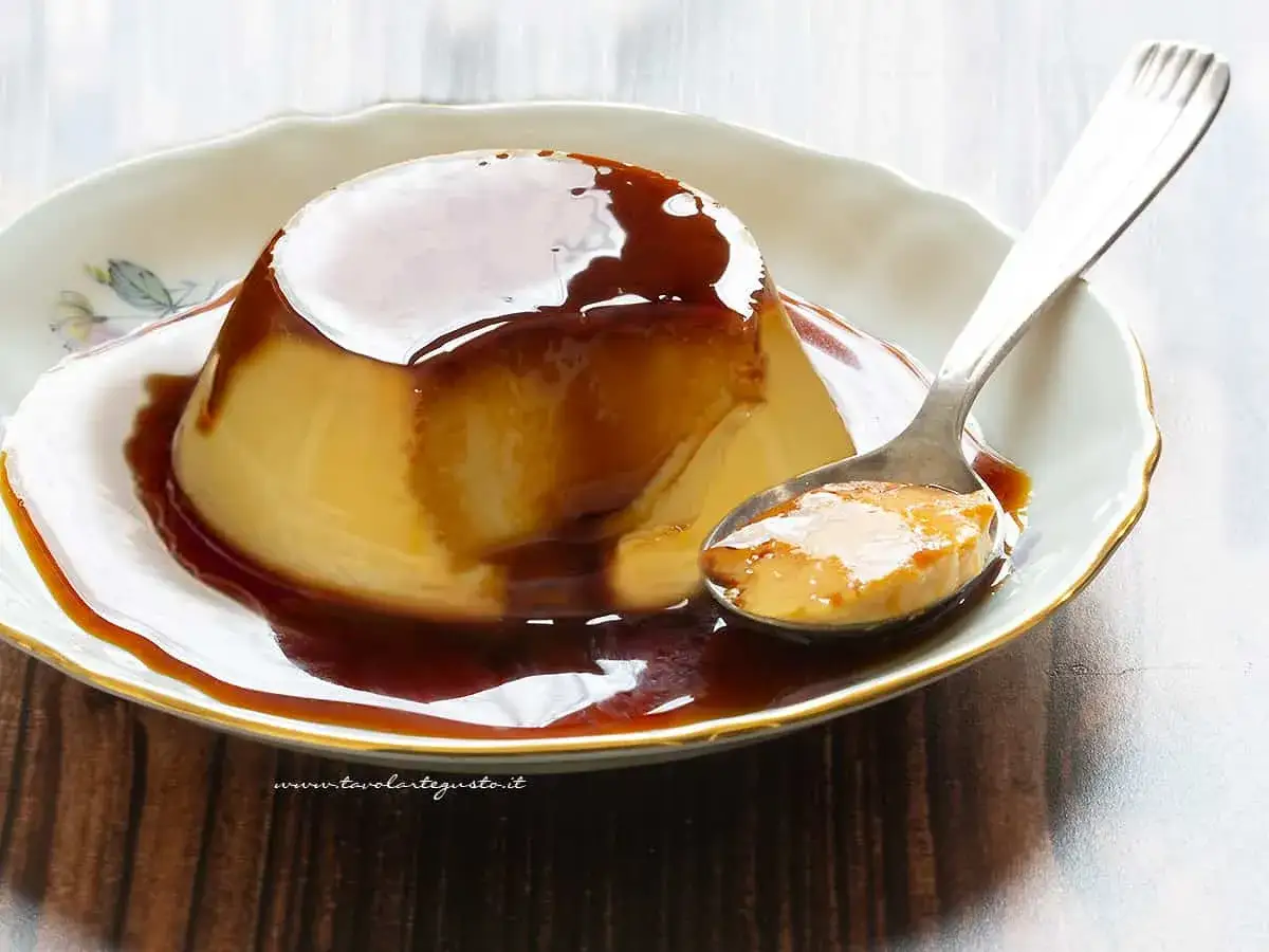 Un cremoso budino ricoperto da una lucida salsa caramellata, simile al dulce de leche, pronto per essere gustato.