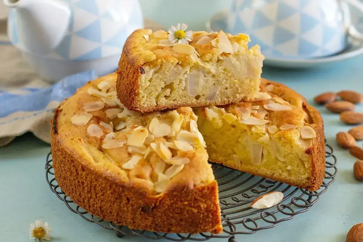 Deliziosa torta pere con mandorle a lamelle, guarnita con un fiorellino bianco. Perfetta per una pausa golosa.