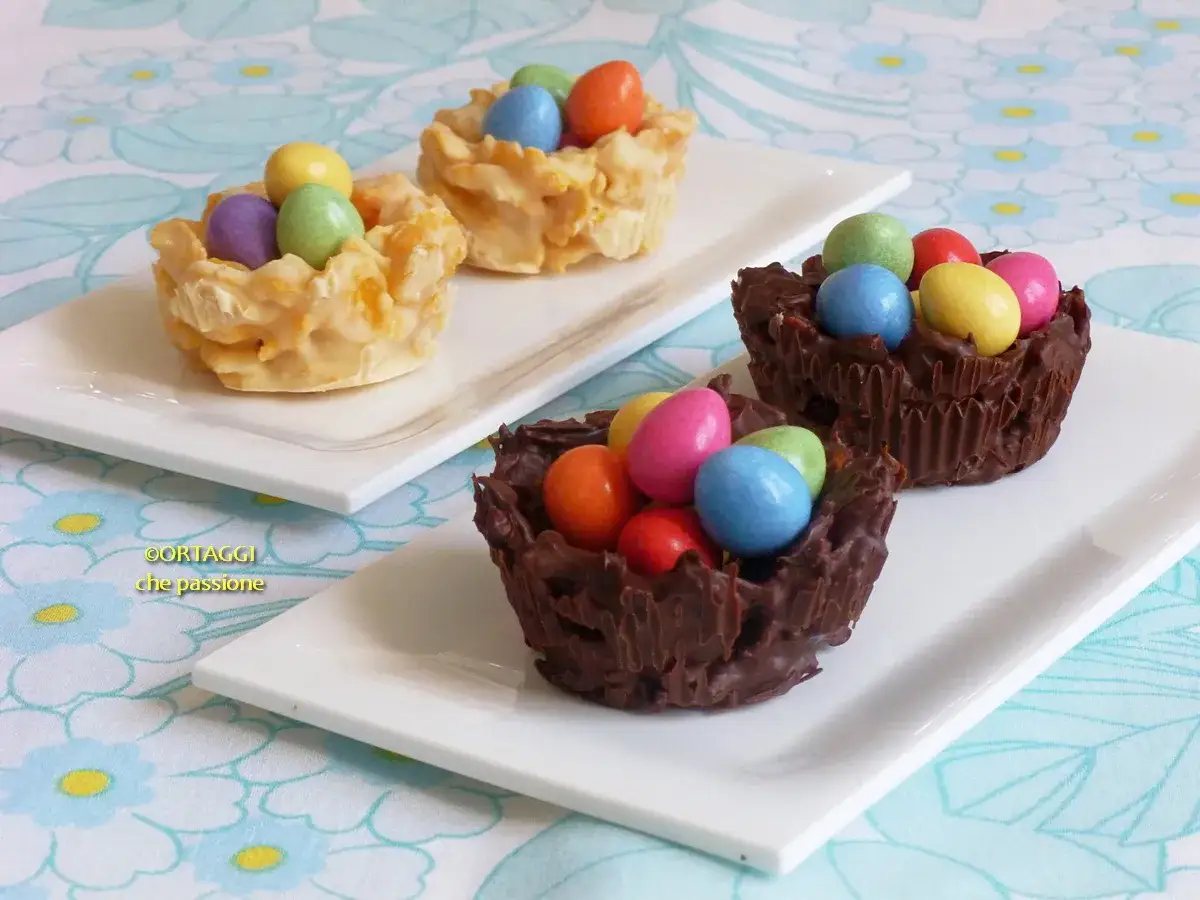 Deliziosi nidi di Pasqua in cioccolato e meringa, ripieni di colorate uova di cioccolato.