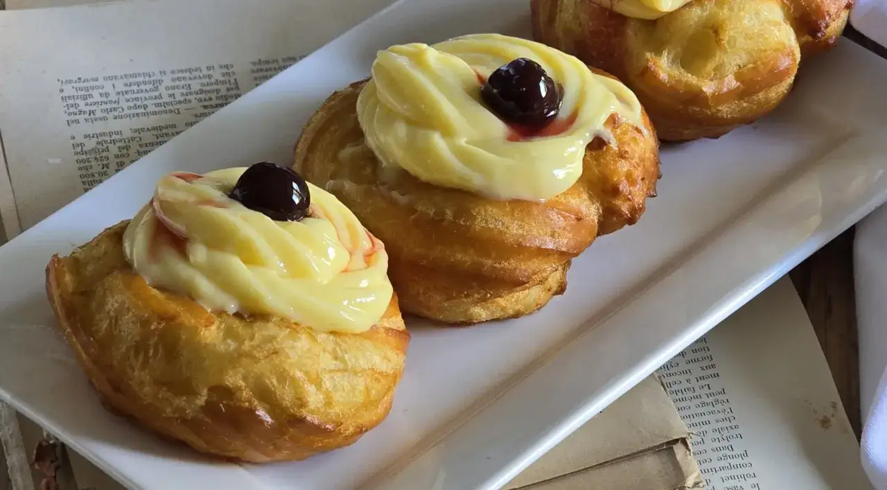Zeppole di San Giuseppe, dolci soffici con crema pasticcera e ciliegina, un classico della tradizione.