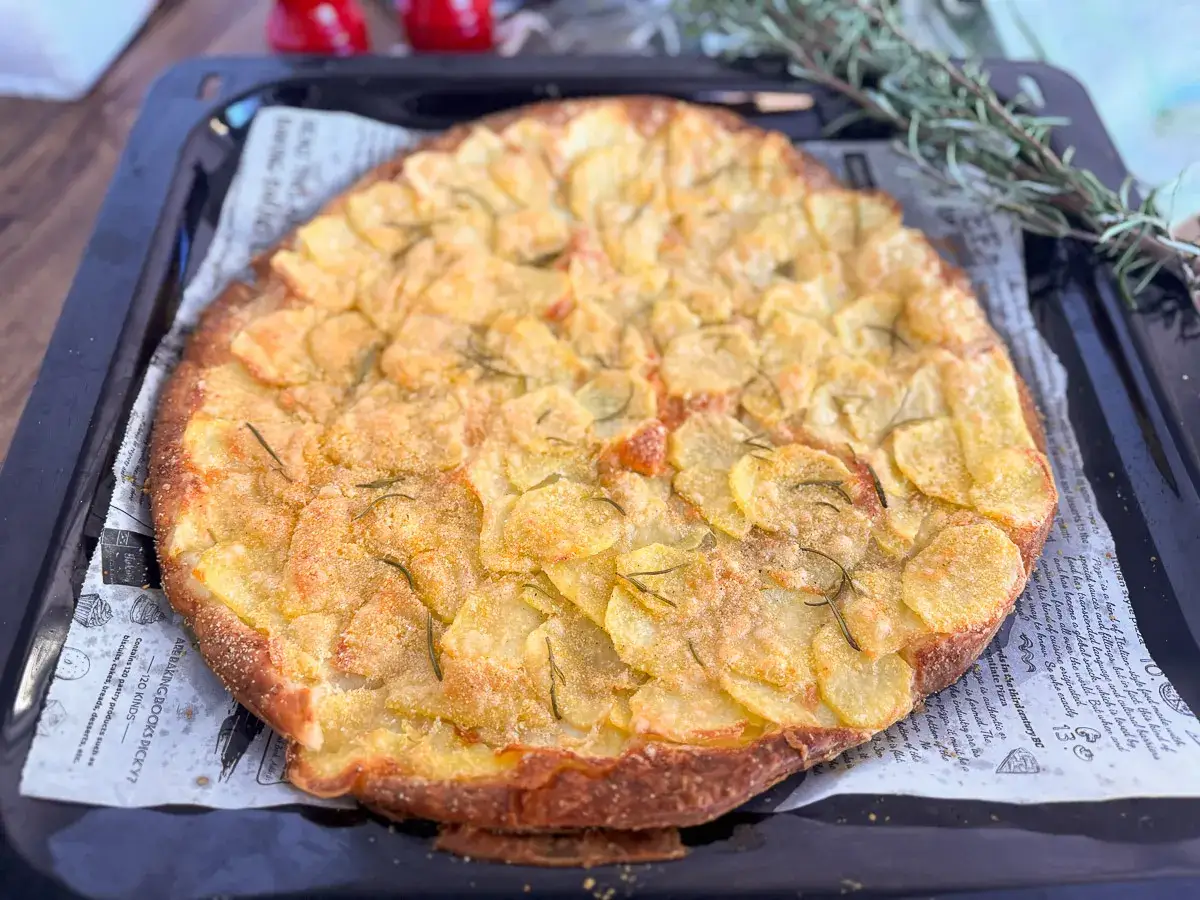 Focaccia con patate e rosmarino, appena sfornata, pronta per la cottura della pasta sfoglia.