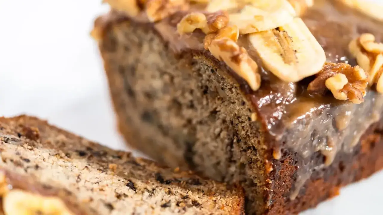 Fetta di banana bread cacao con glassa lucida, noci e fettine di banana.