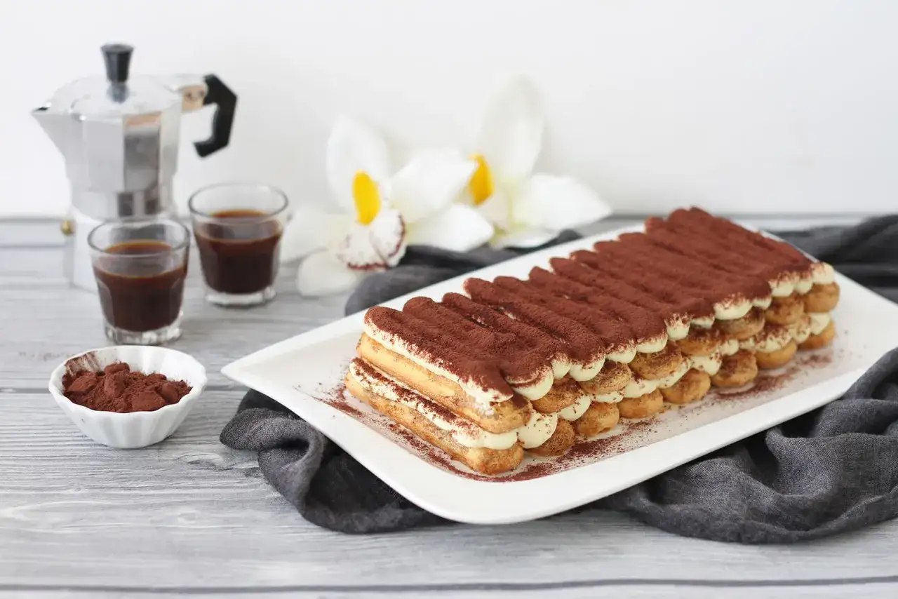 Tiramisù pronto da gustare, con savoiardi, crema e cacao. Gli ingredienti tiramisù sono pronti per un dolce perfetto.