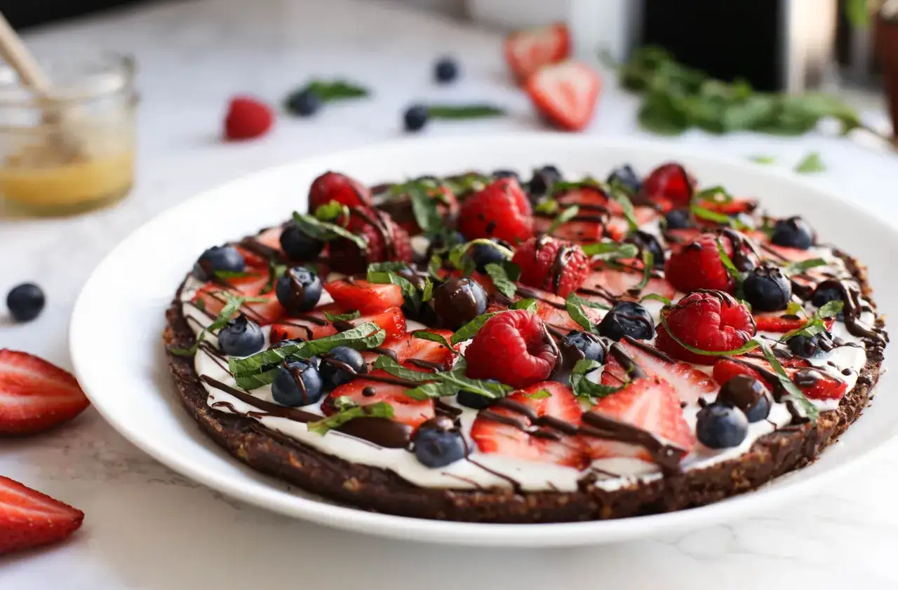 Deliziosa pizza al cioccolato con fragole, mirtilli, lamponi e menta fresca.