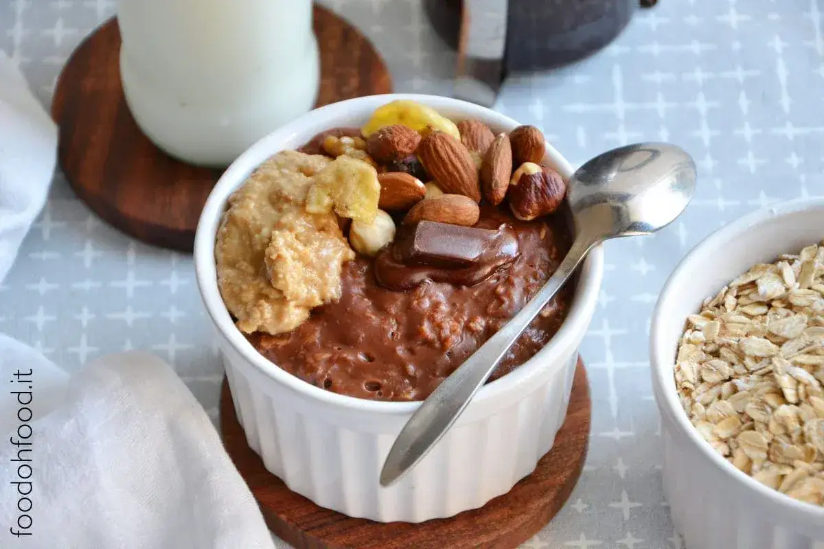 Porridge al cioccolato con burro d'arachidi, frutta secca e banana. Un delizioso mix di cereali e cioccolato per iniziare la giornata.