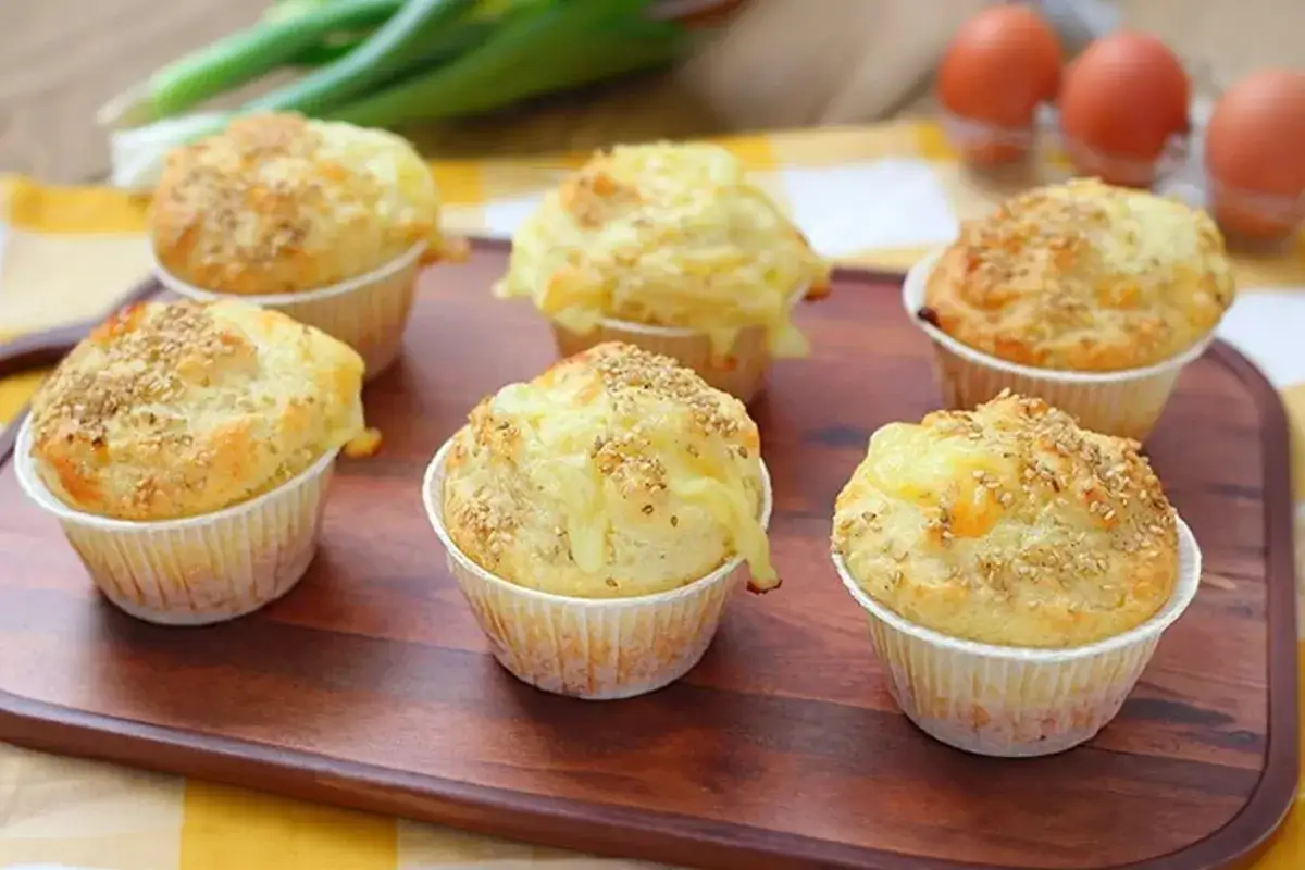Sei muffin salati, con formaggio fuso e semi di sesamo, pronti per essere gustati. L'impasto per muffin &egrave; soffice e dorato.