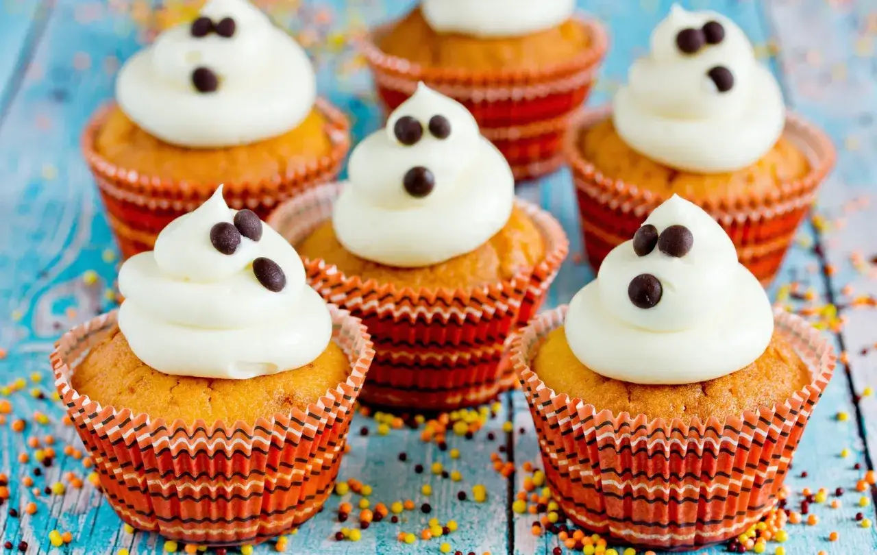 Muffin Halloween facili a forma di fantasmino, decorati con glassa bianca e gocce di cioccolato.
