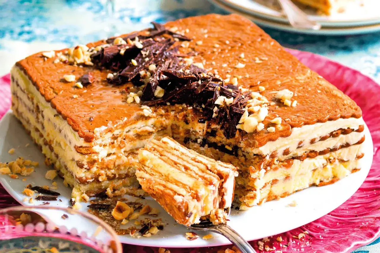 Torta fredda a strati con biscotti, crema al burro e scaglie di cioccolato. Una fetta &egrave; gi&agrave; stata prelevata con una forchetta.