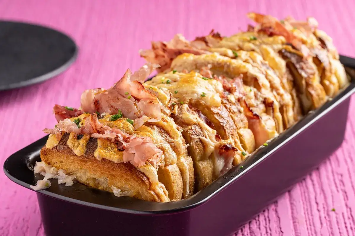 Plumcake farcito con prosciutto e formaggio fuso, tagliato a fette e pronto per essere gustato.