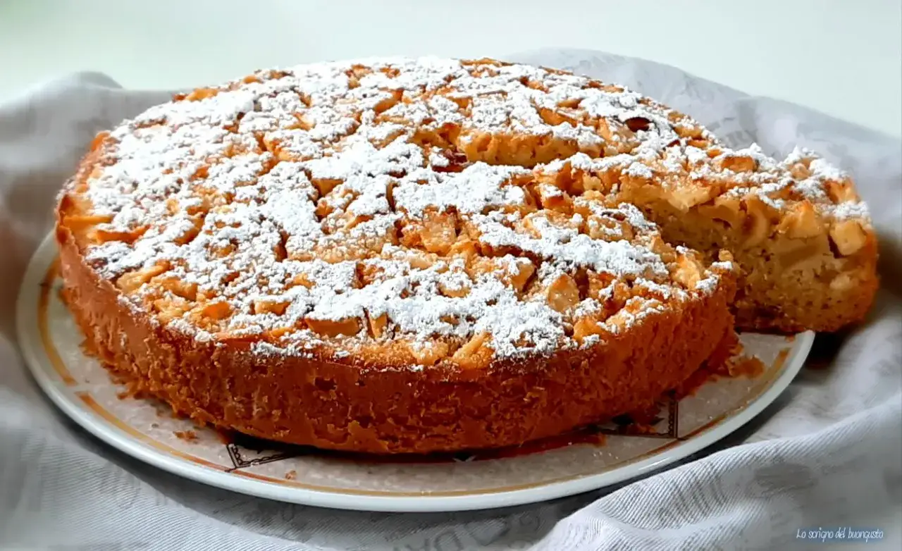 Ciambella romagnola con mele e mandorle, cosparsa di zucchero a velo. Un dolce profumato e invitante.