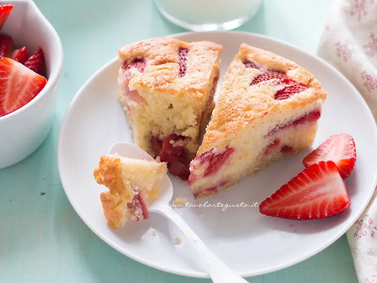 Fette di torta di fragole e yogurt, soffice e profumata, con fragole fresche e una cucchiaiata assaggiata.