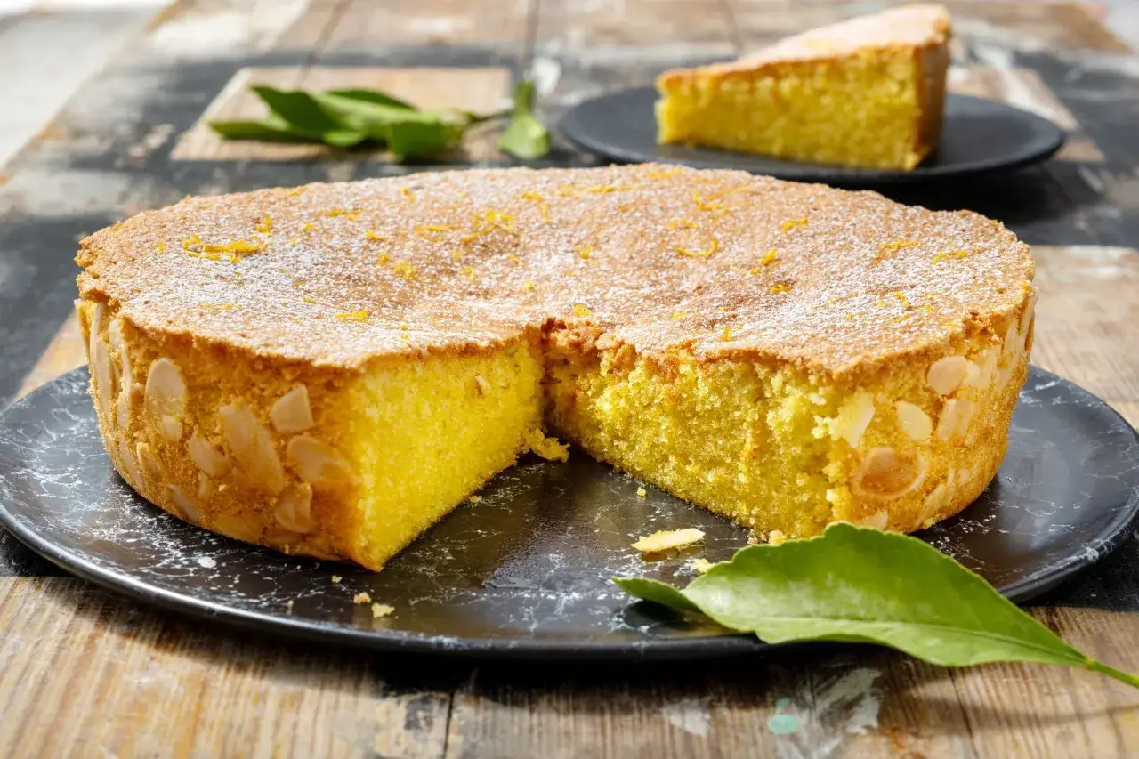 Una deliziosa caprese al limone, cosparsa di zucchero a velo e mandorle, pronta per essere gustata.