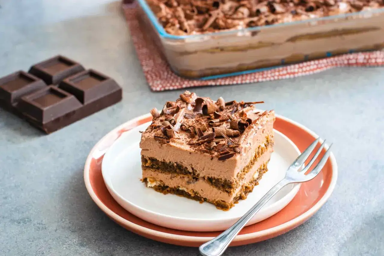 Una fetta di tiramisù al cioccolato e mascarpone, guarnita con riccioli di cioccolato, pronta per essere gustata.