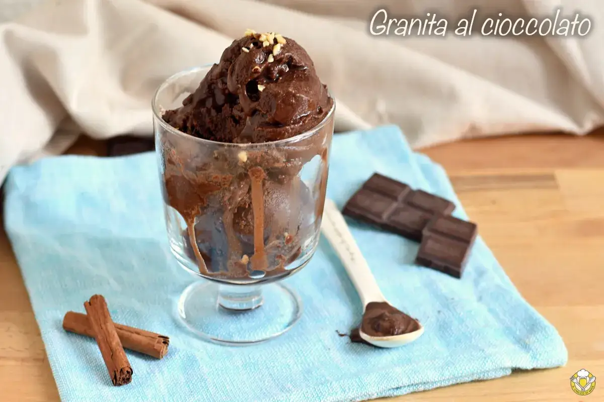 Deliziosa granita al cioccolato in un bicchiere, con pezzi di cioccolato e cannella accanto.