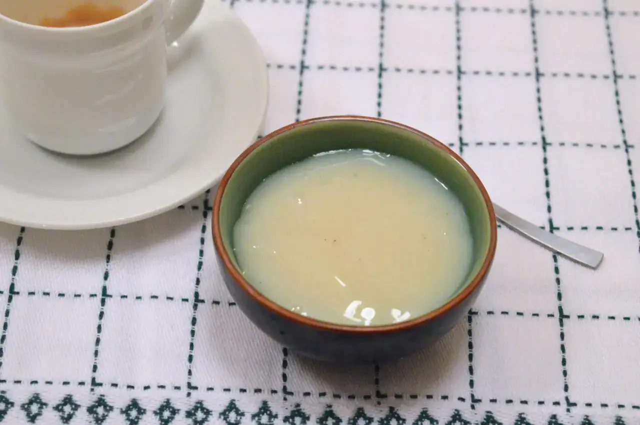 Una ciotola di latte condensato bimby, cremoso e invitante, accanto a una tazza di caff&egrave;.