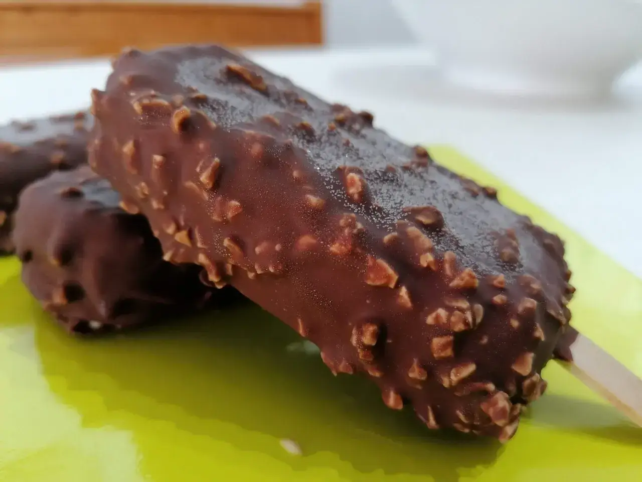 Due semifreddi al cioccolato ricoperti di granella di nocciole su un piatto verde brillante.