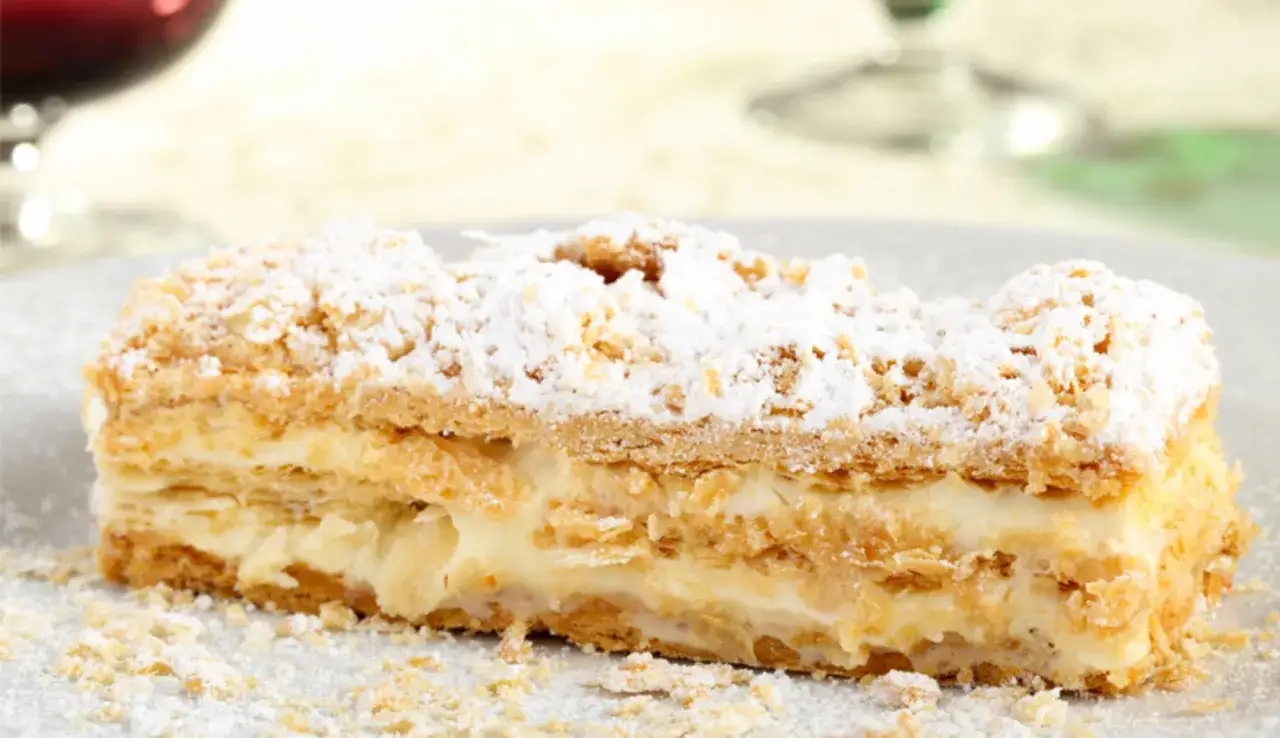 Una fetta di torta millefoglie con crema pasticcera e zucchero a velo, pronta per essere gustata.